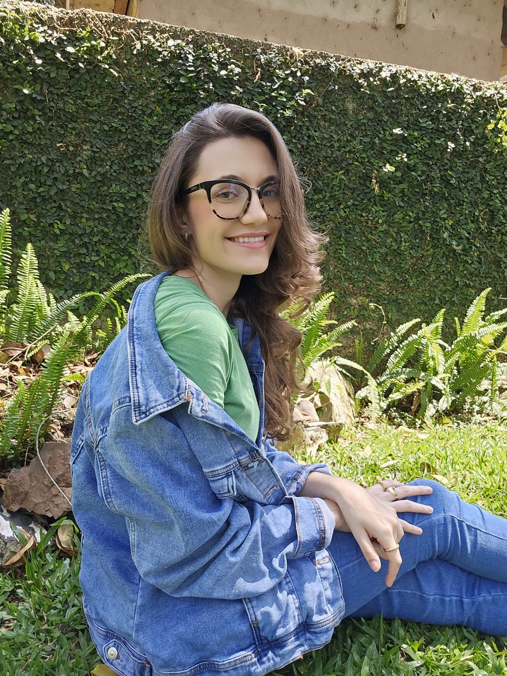 Teacher Ana Kalil sentada em um jardim, sorrindo